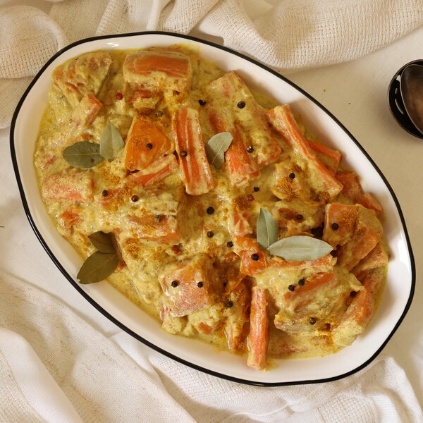 Un plat contenant des carottes, des patates douces et des poivrons mijotés dans une sauce au lait de coco et au cari.