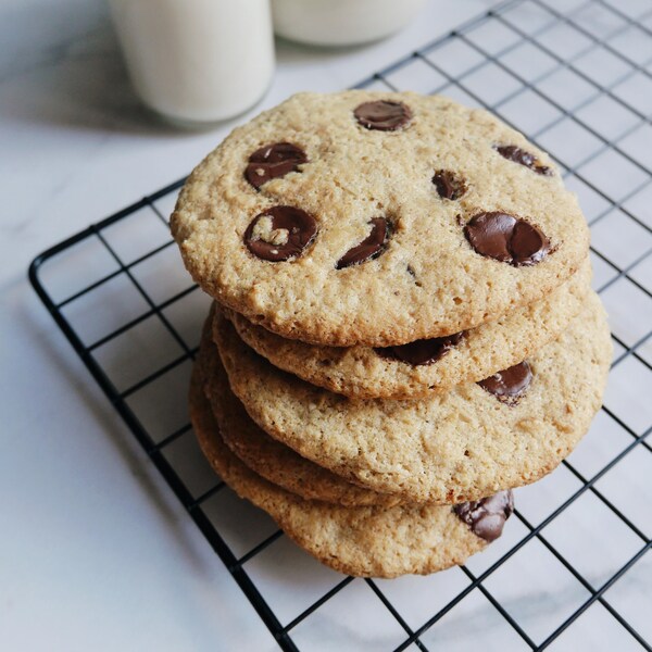 Sur une grille à pâtisserie, se trouve des biscuits au chocolats empilés.