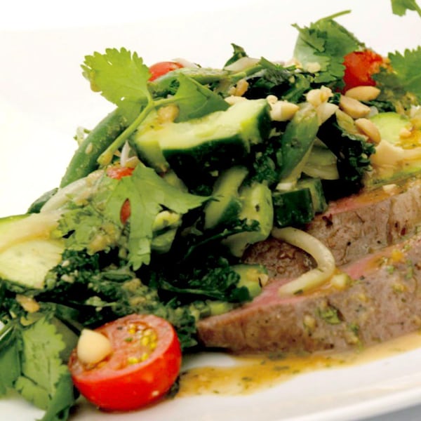 Des morceaux de bœuf avec de la salade par-dessus.