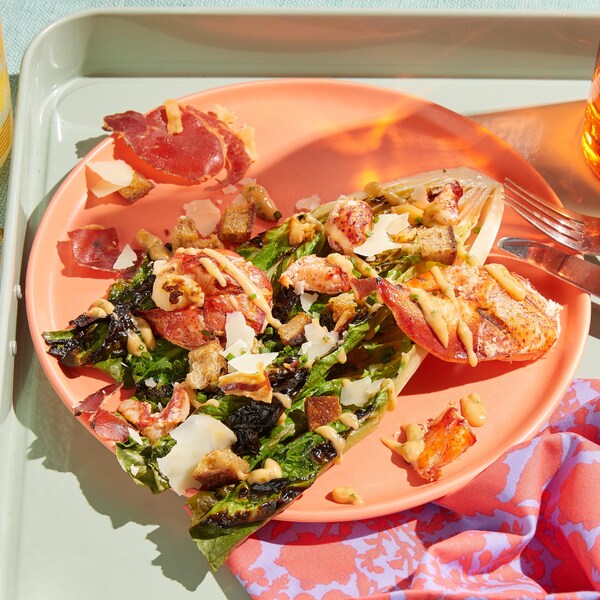 Dans une assiette, une demi laitue grillée avec du homard et de la vinaigrette césar.