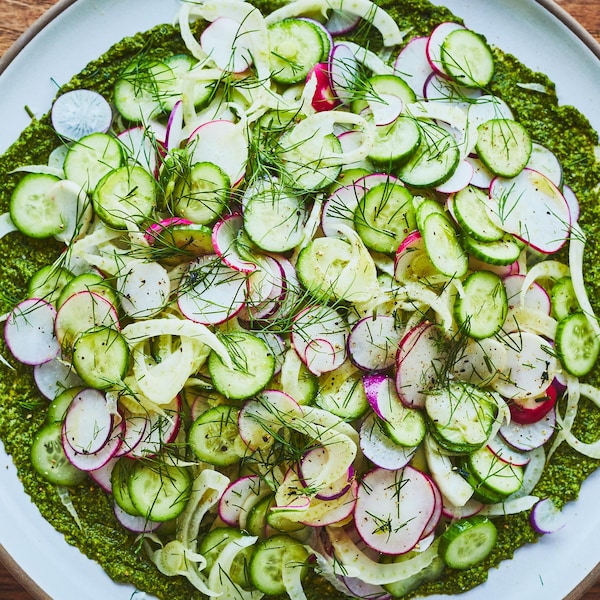 Une assiette avec du pesto garni de radis, concombres et fenouil.