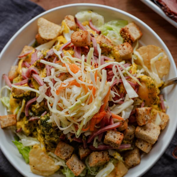 Un bol de salade de viande fumée, de salade de chou et de croûtons.