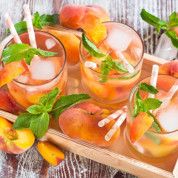 Trois verres de sangria blanche avec des pêches et de la menthe.