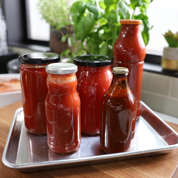 Des bouteilles en verre de différents formats remplis de sauce tomate.