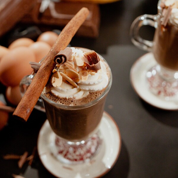 Smoothie au café dans un verre garni de crème fouetté, amandes effilées, copeaux de chocolat et d'un bâton de cannelle.