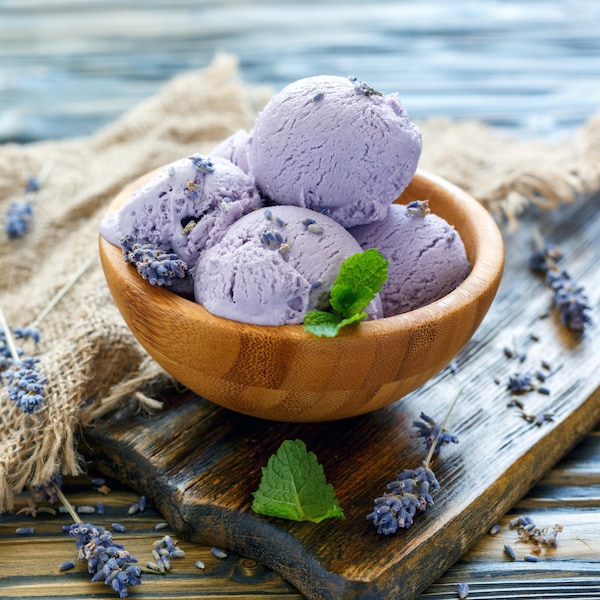 Un petit bol en bois rempli de plusieurs boules de crème glacée violettes à la lavande.