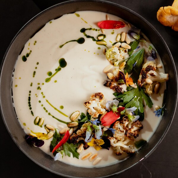 Un bol de soupe garni de chou-fleur, d'herbes et de pétales de fleurs.