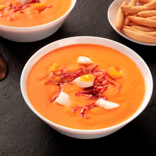 2 bols de soupe aux tomate, du jambon et des oeufs sur la soupe.