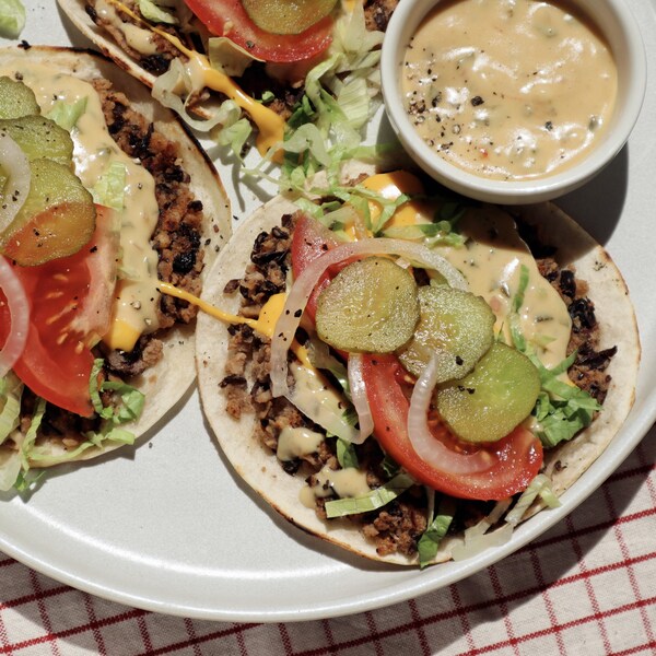 Trois tacos végétaliens dans une assiette avec un petit bol de sauce.