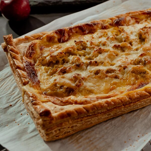 Une tarte salée aux poireaux et à la sauce béchamel sur une grille sortant du four.