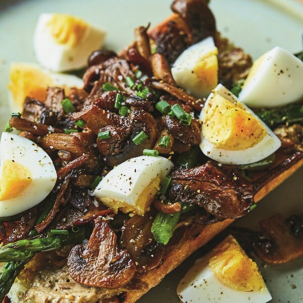 Une tartine de champignon servie avec des morceaux d'œuf cuit dur et des asperges.