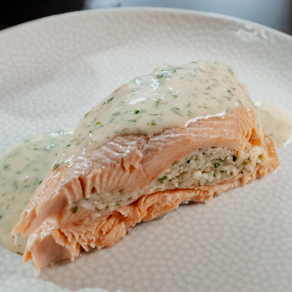 Un morceau de truite garni de mousseline de crevettes et recouvert de sauce aux herbes.