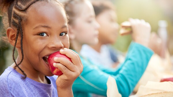 Une enfant mange une pomme.