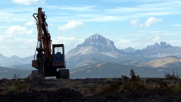 Une pelle mécanique inoccupée aux environs du mont Grassy, avec le mont Crowsnest en arrière-plan, photographié en 2014.