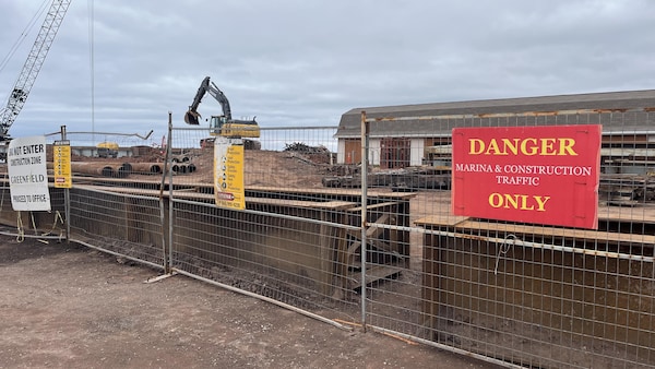 Des barrières délimitent le site de construction. Une grue et une pelleteuse s'activent sur le futur nouveau quai d'Abram-VIllage.