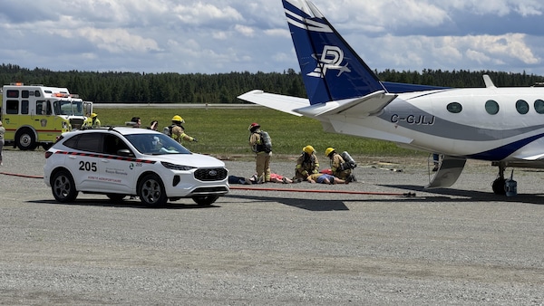 Des pompiers en exercice devant un avion dans un aéroport.
