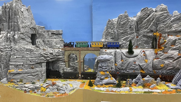Une maquette de train miniature passant à travers des rochers, paysage d'automne.