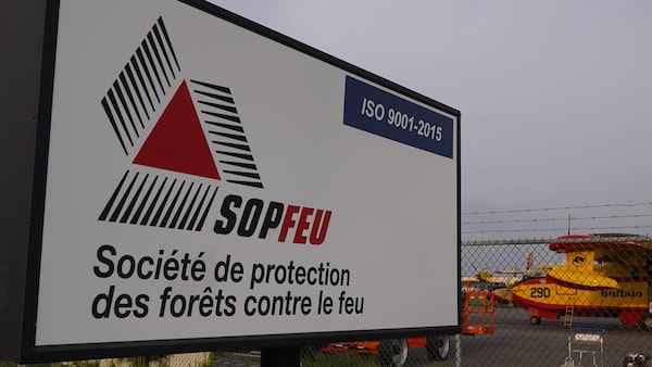Deux avions-citernes sur le tarmac de l'aéroport de Val-d'Or. Une pancarte annonce les bureaux de la Société de protection des forêts contre le feu.
