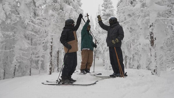 Trois skieurs lèvent leur bras dans les airs. 
