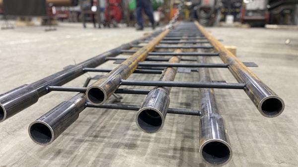 Des pièces en acier sont déposées au sol à l’intérieur d’une usine.
