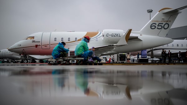 Des gens travaillent près d'un avion Bombardier 650 Challenger garé dans un aéroport.