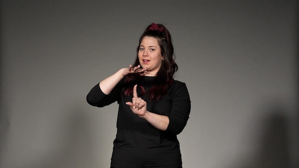 Une femme communique avec la langue des signes du Québec.