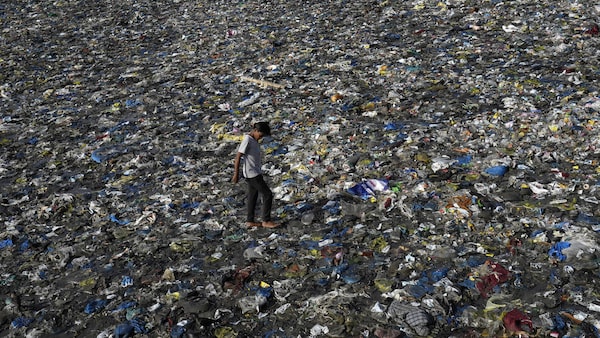 Un garçon marche au milieu de déchets, dont beaucoup sont en plastique, sur la plage de Badhwar Park, à Mumbai, en Inde, le 5 juin 2023.