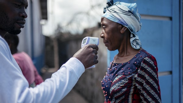 Un employé d'un hôpital de Goma prend la température d'une visiteuse à l'aide d'un thermomètre infrarouge sans contact.