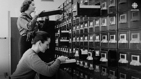 Deux employées, Jacqueline Farley et Charlotte Ferland, consultent des fiches dans un classeur.