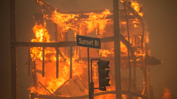 Un immeuble en flammes derrière un panneau affichant Sunset Bl.