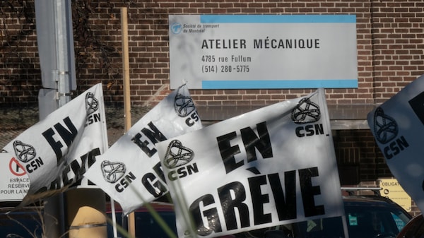 Des drapeaux « En grève CSN » flottent devant un atelier mécanique de la Société de transport de Montréal au 4785, rue Fullum.
