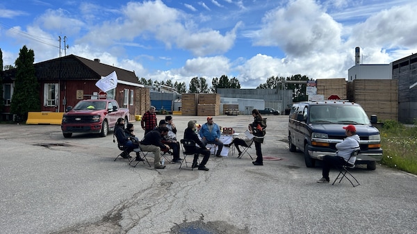 Des membres du groupe Première Nation Mamo assis ensemble devant les installations.