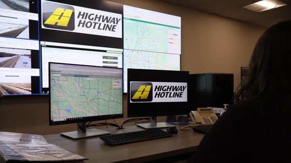 Une personne assise à un bureau regarde des écrans et des cartes des conditions routières.