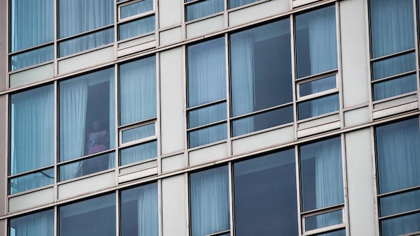 Une personne regarde à l'extérieur de sa chambre d'hôtel.