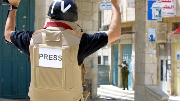 Un photographe de l'AFP lève les mains alors qu'un soldat israélien pointe son arme sur un groupe de journalistes pour les éloigner, dans la ville de Bethléem, en Cisjordanie occupée, le 11 avril 2002. 