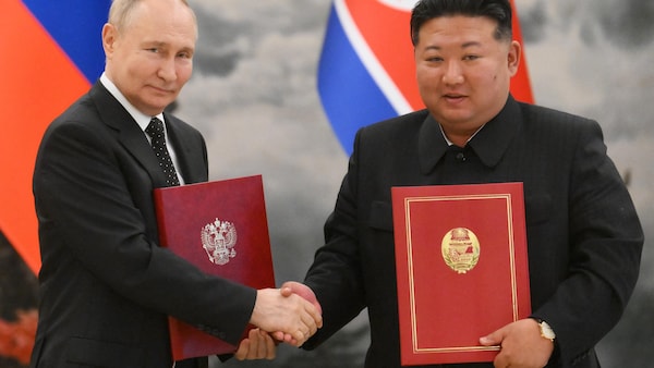 Vladimir Poutine et Kim Jong-un se serrent la main en tenant chacun une copie du traité entre es deux pays.