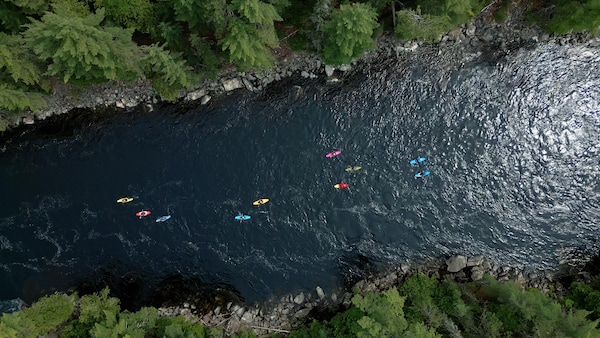 Vue aérienne de kayaks descendant une rivière calme.
