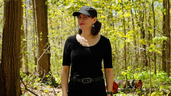 Une femme habillée en noir dans une forêt.
