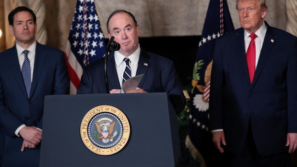 Un homme s'adresse aux journalistes au côté de Donald Trump.