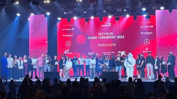 Les chefs honorés debout sur scène et la mascotte Michelin lors de la cérémonie du Guide Michelin de Toronto.