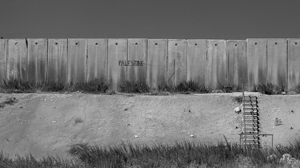 Un long mur de béton porte l'insciption Palestine. 