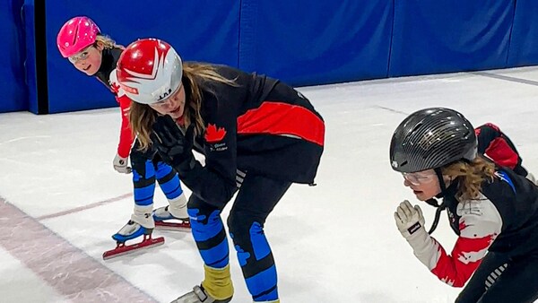 Nicole est accompagnée de deux jeunes filles sur la ligne de départ d'un circuit de patinage de vitesse.