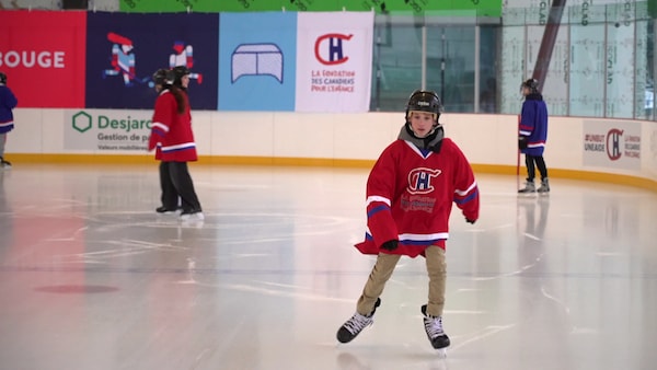 Un jeune garçon patine sur une patinoire couverte.