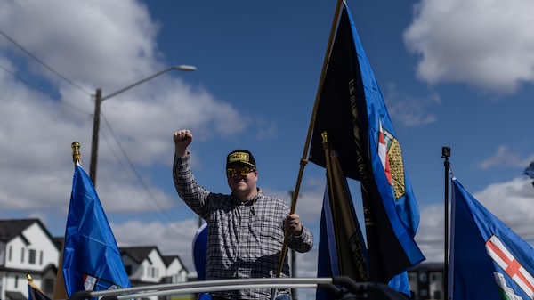 Une personne agite un drapeau sur le toit d'un véhicule.