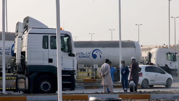 Quatre hommes parlent près de deux camions-citernes. 