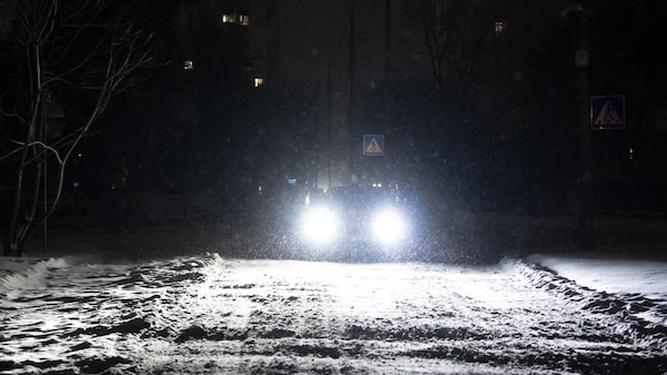  Une voiture, phares allumés, roule sur une route non éclairée.