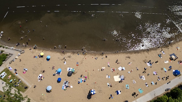 Une photo aérienne de la plage de Verdun, où plusieurs personnes sont installées sur le sable et où d'autres personnes se baignent dans de l'eau brunâtre, le 30 juin 2025.