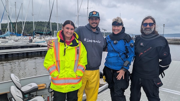 Quatre personnes posent pour la photo sur un quai de bateaux.