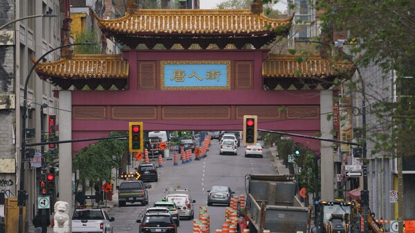 Une vue d'ensemble des portes du quartier chinois de Montréal, sous lesquelles circule un trafic dense parmi des cônes de construction.