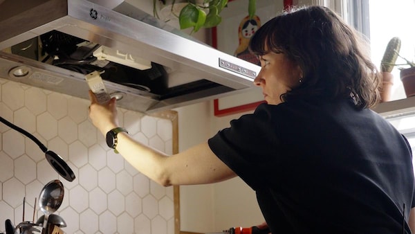 Une femme tente de réparer une hotte de four